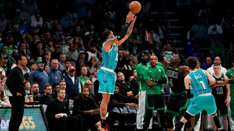 Charlotte Hornets forward Miles Bridges, left, shoots the ball for a score under pressure from...