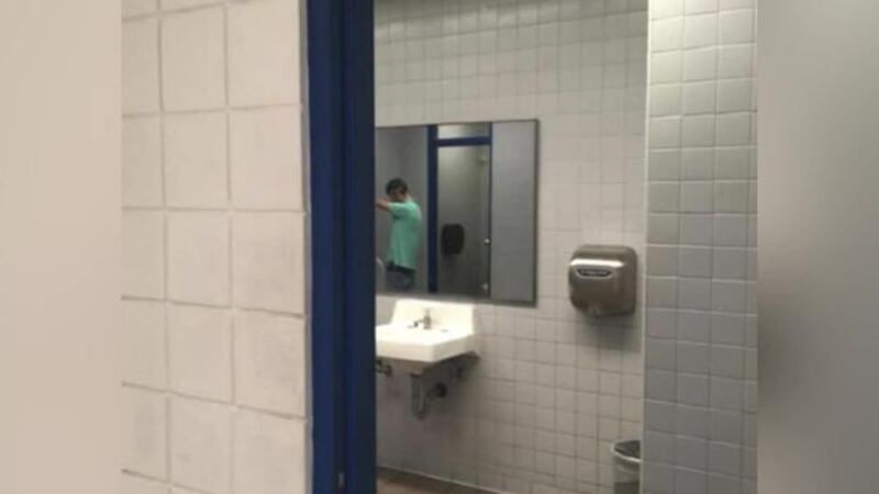 A staged photo taken from the hallway shows a senior standing at a urinal. (Source: WFTS/CNN)